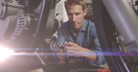 Male Mechanic Concentrated on Motorbike Repair in Garage