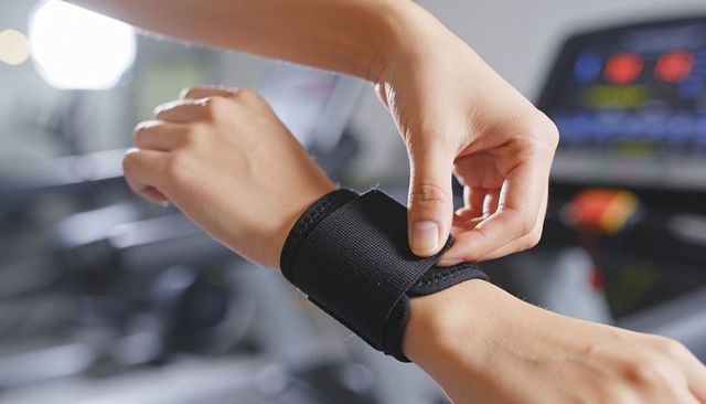 Athlete securing neoprene wrist strap before treadmill workout close-up