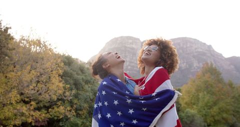 Friends Embracing with American Flag Outdoors