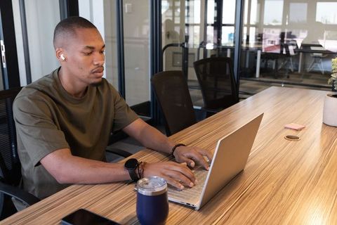 African american man working on laptop in modern coworking office, focused remote work
