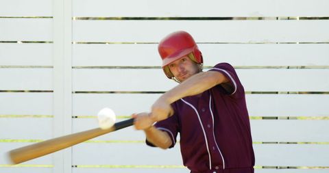 Baseball player hitting ball during practice on sunny day