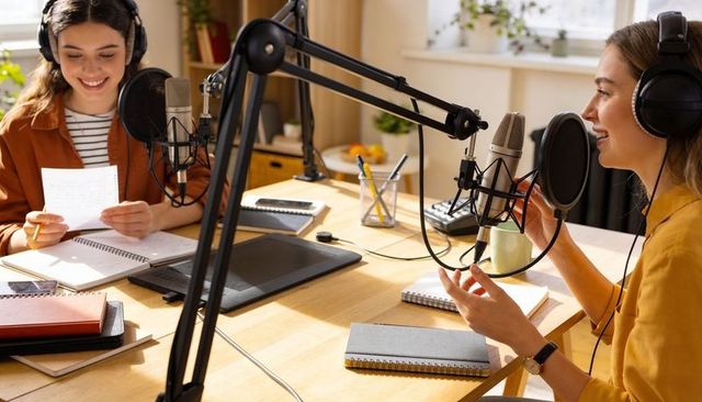 Female co-hosts recording podcast at home studio, collaborating and conversing naturally