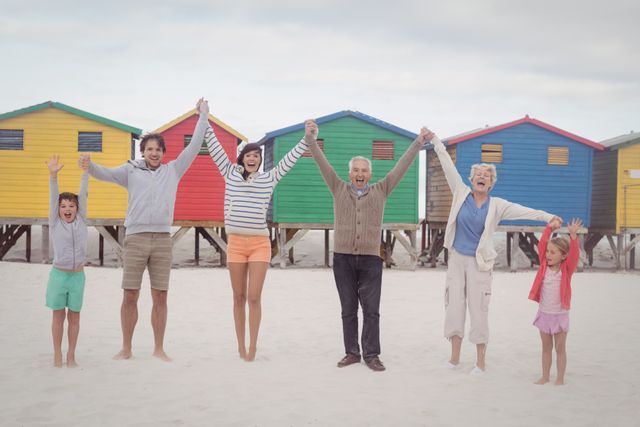 Portrait of cheerful multi-generation family holding hands while standing at beach
