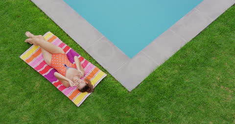 Caucasian Woman Relaxing by Pool in Backyard