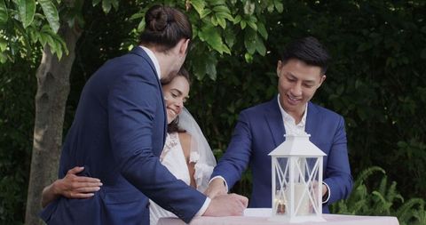 Groom signing wedding document outdoors with smiling guests