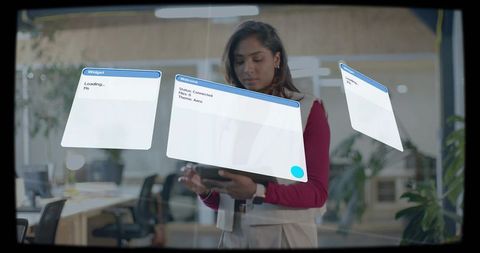 Businesswoman interacting with holographic interface using tablet in modern office glass