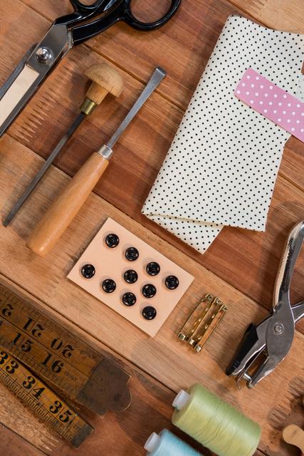 This image showcases a variety of sewing tools and materials neatly arranged on a wooden table. Items include scissors, fabric, buttons, a measuring tape, thread, and other sewing accessories. Ideal for use in articles or advertisements related to sewing, crafting, DIY projects, tailoring, or handmade goods. Perfect for illustrating blog posts, tutorials, or promotional materials for sewing supplies and kits.