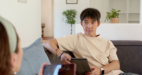 Casual living room conversation with man holding tablet and woman holding smartphone