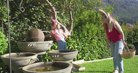 Mother and daughter wearing bunny ears exploring backyard fountain spring easter hunt