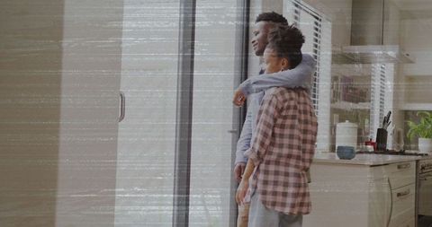 Couple Embracing While Looking Out Kitchen Doorway