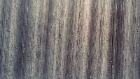 Weathered corrugated metal panel with peeling paint and vertical ribs showing patina