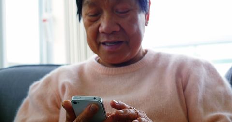 Senior Woman Engaging with Smartphone in Cozy Home Setting