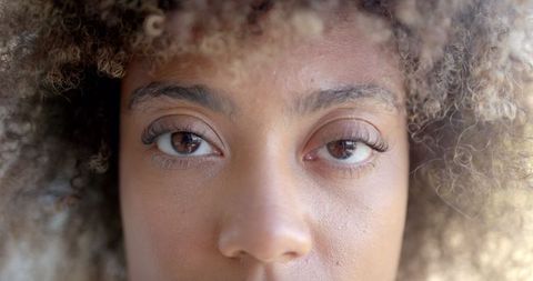 Close-up of Woman's Eyes with Curly Hair and Focused Facial Expression