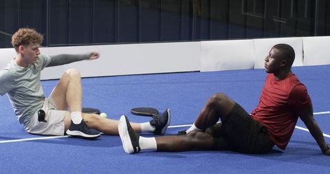 Active Friends Resting on Sports Court with Paddle Equipment