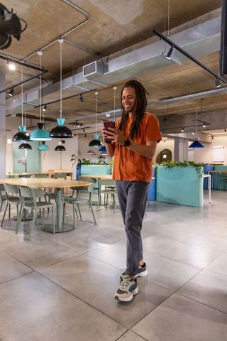 Man walking coworking lounge using smartphone smiling casual modern office interior