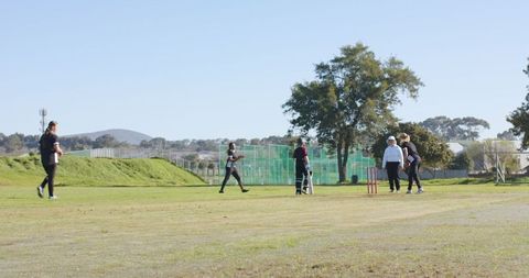 Female Cricket Players Engaged in Outdoor Game on Green Field