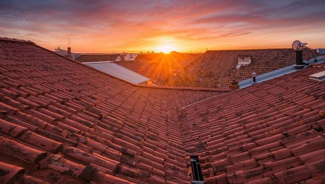 Sunburst over terracotta roof valley casting golden hour light across weathered urban tiles