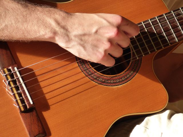 Hand strumming acoustic guitar strings details heartfelt performance or practice. Ideal for music blogs, tutorials, and promotional material.