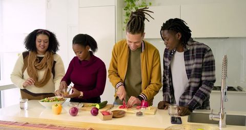 Preparing meal together chopping red pepper and mixing salad at modern kitchen island