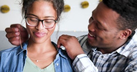 Man Giving Woman Necklace at Celebration Smiling Happily