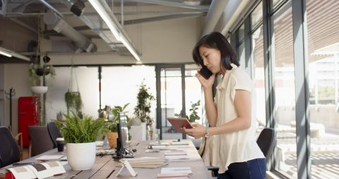 Asian Professional Woman Taking Call in Modern Bright Office