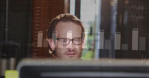 Man in Eyeglasses Analyzing Digital Data in Modern Workplace Environment