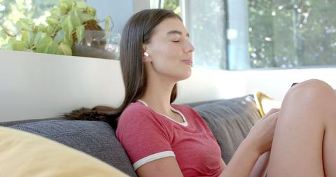 Teenage Girl Relaxing with Smartphone on Couch at Home