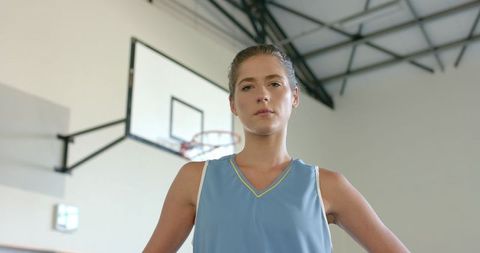 Determined Female Athlete in Gym Setting Demonstrating Focus Before Basketball Hoop