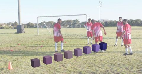 Five male soccer players practicing passing drill on grass field with training cones