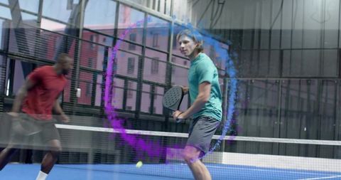 Padel match returning low ball preparing forehand on blue indoor court with purple motion