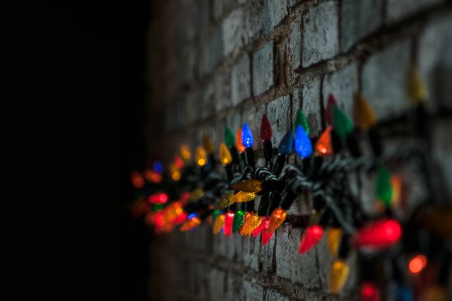 Colorful fairy lights draped on a brick wall creating a festive and celebratory atmosphere. Perfect for use in holiday promotions, party invitations, festive decorations ideas, home decor inspiration, and background visuals in festive-themed projects.