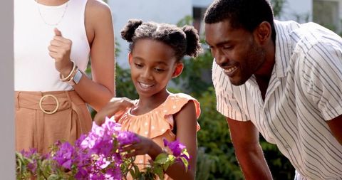 Family enjoying garden time with daughter amid blooming purple flowers