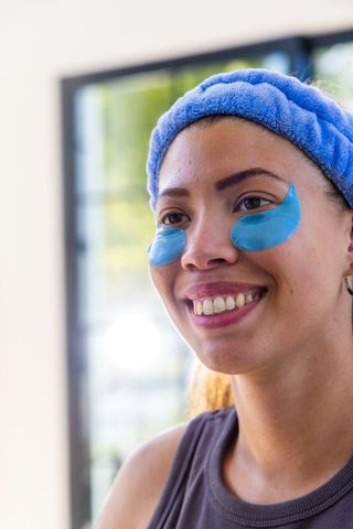 Smiling african american woman wearing blue hydrogel under-eye patches and headband