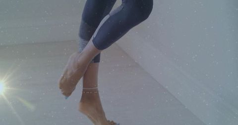 Barefoot legs wearing cropped leggings and beaded anklet in minimalist home corner