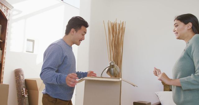 Couple in their new home excitedly unpacking boxes together. This can be used in advertisements promoting moving services, home decor products, or furniture stores. Ideal for blogs about moving house or starting new life chapters. Represents teamwork and family bonding in a positive light.