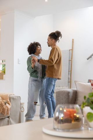 Couple dancing and holding hands in cozy living room sharing intimate moment