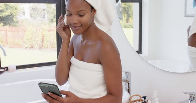 Woman With Towel Wrapped Body Applying Skincare While Using Smartphone - Download Free Stock Images Pikwizard.com