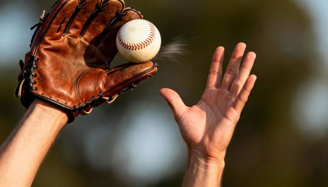 Catching baseball with brown leather glove and bare hand reaching closeup during golden hour