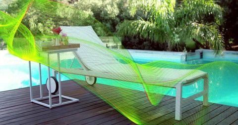 Modern white chaise lounge by turquoise pool on deck with neon overlay and palms