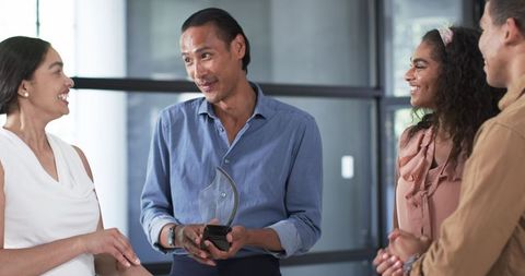 Diverse group celebrating workplace achievement in modern office