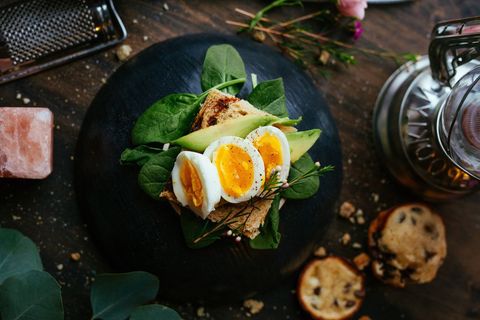 Gourmet avocado toast with soft-boiled eggs on rustic whole-grain bread and spinach