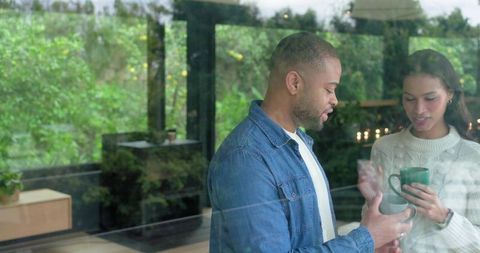 Cozy couple sharing morning coffee by window, intimate moment with green mug