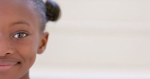 African girl smiling gently half-portrait with hair buns on minimal high-key background