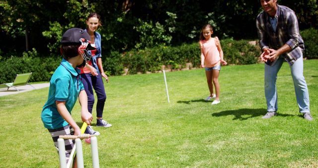 A family enjoys a game of cricket in a sunny backyard, with copy space - Download Free Stock Photos Pikwizard.com