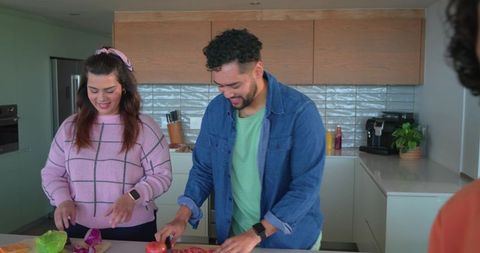 Friends chopping vegetables on modern kitchen island preparing healthy meal together
