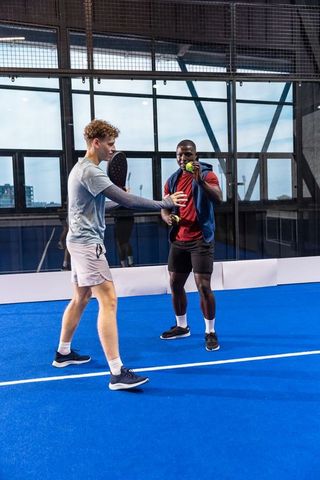 Diverse friends practicing padel on blue court - urban training, teamwork and athletic performance