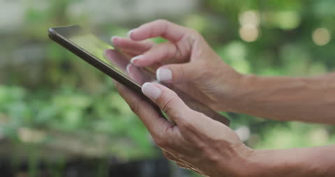 Woman Using Tablet in Sunny Garden