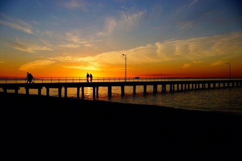 Silhouette of Couple on Pier at Vibrant Sunset