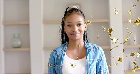 Young woman standing in modern home interior wearing blue plaid shirt with gold star overlay