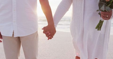 Senior Couple Holding Hands at Beach Sunset Celebrating Love